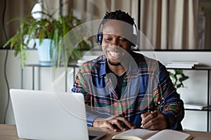 Cheerful young african american man in headphones listening educational lecture.