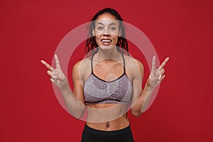 Cheerful young african american sports fitness woman in sportswear posing working out isolated on red wall background