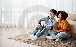 Cheerful young african american woman and man gamers play at computer game with joystick