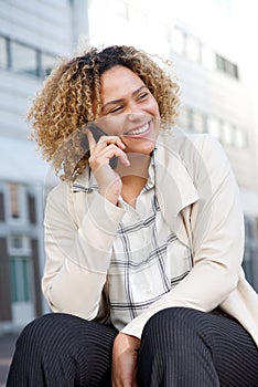 Cheerful young african american woman talking on mobile phone in city