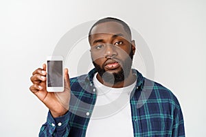 Cheerful young African male in shirt making transaction using mobile naming application on his smart phone.