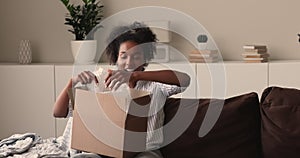 Cheerful young african mixed race woman opening cardboard box.