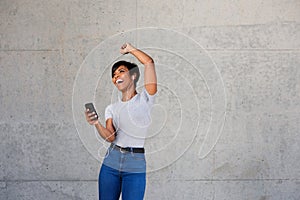 Cheerful young african woman with earphones and mobile phone listening to music