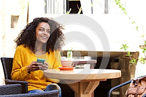 Cheerful young african woman sitting at outdoor cafe