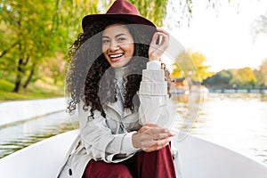 Cheerful young african woman wearing coat riding in a boat