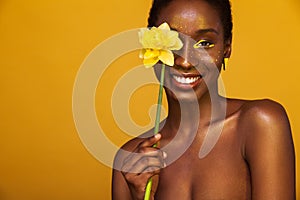 Cheerful young african woman with yellow makeup on her eyes. Female model laughing against yellow background with yellow