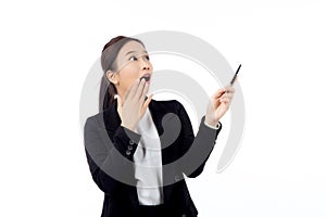 A cheerful young asian businesswoman in a suit, smiling and looking up, holding a pen, celebrating a success isolated.