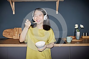 Cheerful Young Asian Girl Eating Meal In Kitchen