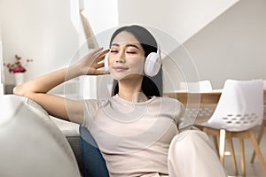 Cheerful young Asian student girl relaxing with favorite ambient tunes