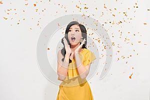 Cheerful young Asian woman celebrating with colorful confetti  on white background