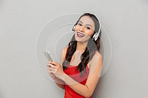 Cheerful young asian woman using mobile phone listening music.