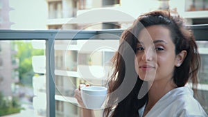 Cheerful young attractive lady smiling while looking at camera holding cup of tea in hands. Beautiful Caucasian happy