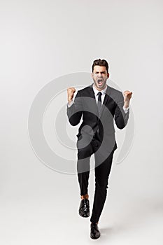 Cheerful young bearded business man show hand up excited with clenched fists. Full length portrait business man isolated