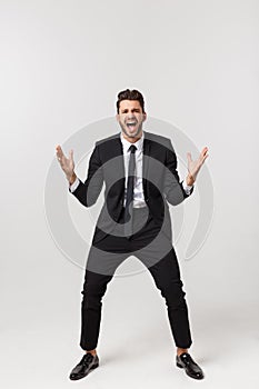 Cheerful young bearded business man show hand up excited with clenched fists. Full length portrait business man isolated