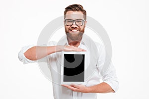 Cheerful young bearded man showing display of tablet computer.