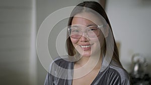 Cheerful young beautiful Asian woman in eyeglasses looking at camera smiling indoors. Portrait of joyful charming slim