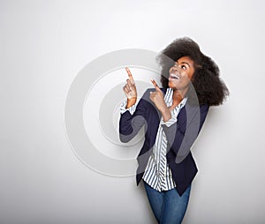 Cheerful young black woman pointing fingers against gray background