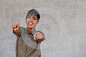 Cheerful young black woman pointing fingers with copy space