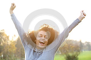 Cheerful young black woman smiling with arms raised