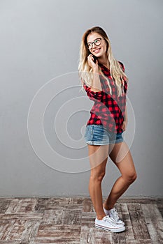 Cheerful young blonde woman talking by phone.