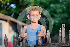Cheerful Young Boy Holding at the Wooden Fence