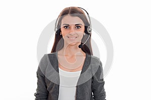 Cheerful young business woman working in call center with headphones and microphone looking at the camera and smiling