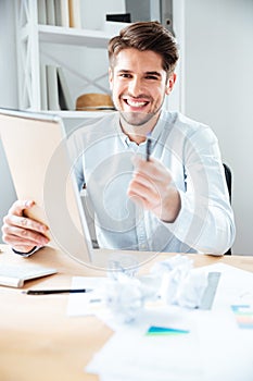 Cheerful young businessman giving notepad and pen to you