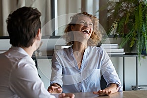 Cheerful young businesswoman enjoying pleasant conversation with colleague.