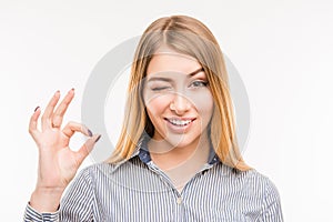 Cheerful young businesswoman gesturing `OK`, close up photo