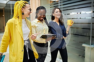 Cheerful young businesswomen having fun while walking in the office building