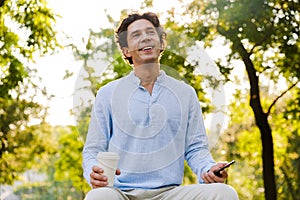 Cheerful young casual man using mobile phone