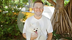 Cheerful young caucasian man with his happy pet dog outside on a park bench, confident and joyful, fully enjoying the vibrant