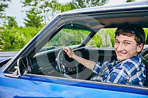 Cheerful young Caucasian man sitting in his car