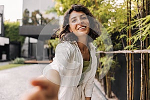 Cheerful young caucasian woman with snow-white smile looks at camera enjoying carefree day.