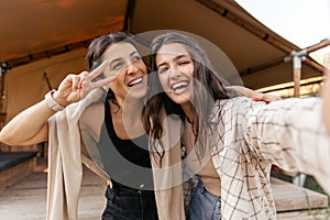 Cheerful young caucasian women laughing posing at camera relaxing outside city near campsite.