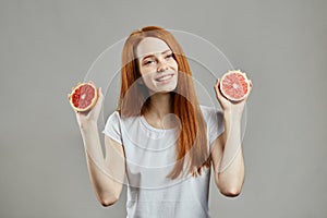 Cheerful young charming girl with grapefruits loking at the camera