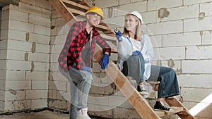 Cheerful young construction workers talking in half-built house