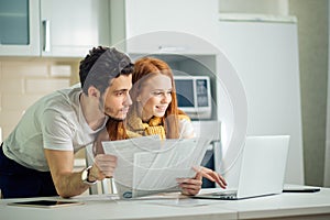 Happy couple at home paying bills with laptop