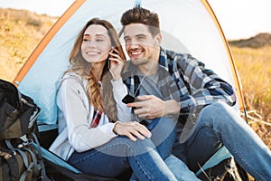 Cheerful young couple camping, sitting