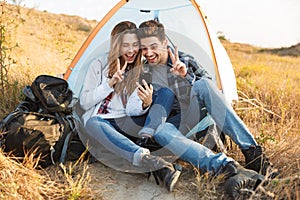Cheerful young couple camping, sitting