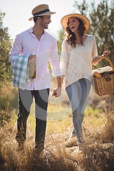 Cheerful young couple carrying picnic basket