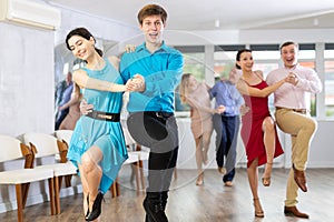 Cheerful young couple dancing playful jitterbug in dance studio