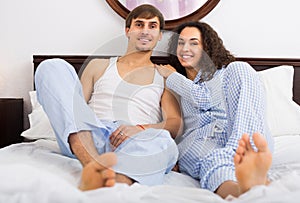 Cheerful young couple in family bed