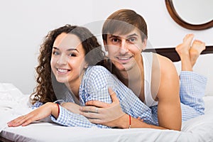Cheerful young couple in family bed