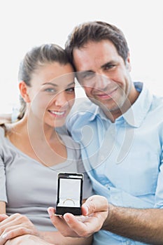 Cheerful young couple getting engaged on the sofa