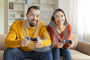 Cheerful Young Couple Having Fun At Home, Playing Video Games Together