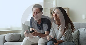 Cheerful young couple playing video games at home, shouldering