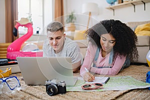 Cheerful young couple preparing and packing for summer beach holiday at home.