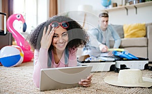 Cheerful young couple preparing and packing for summer beach holiday at home.