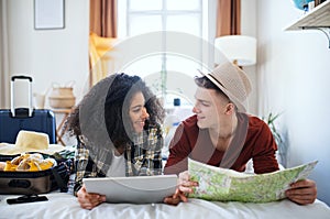 Cheerful young couple preparing and packing for summer holiday at home.